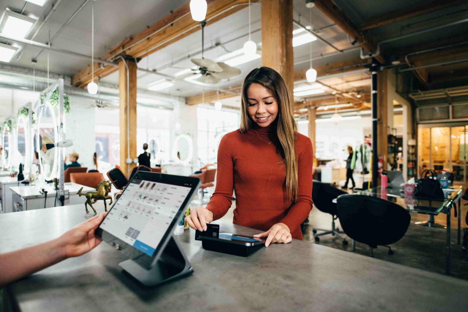Photo d'une femme qui passe sa carte bleue dans un terminal de paiement digital